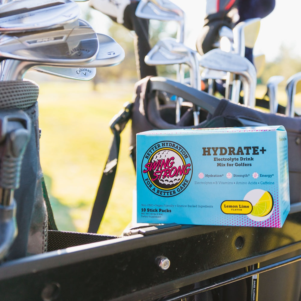 swing strong hydrate+ stick pack electrolyte energy hydration drink mix for golf box sitting on golf cart with golf clubs in background